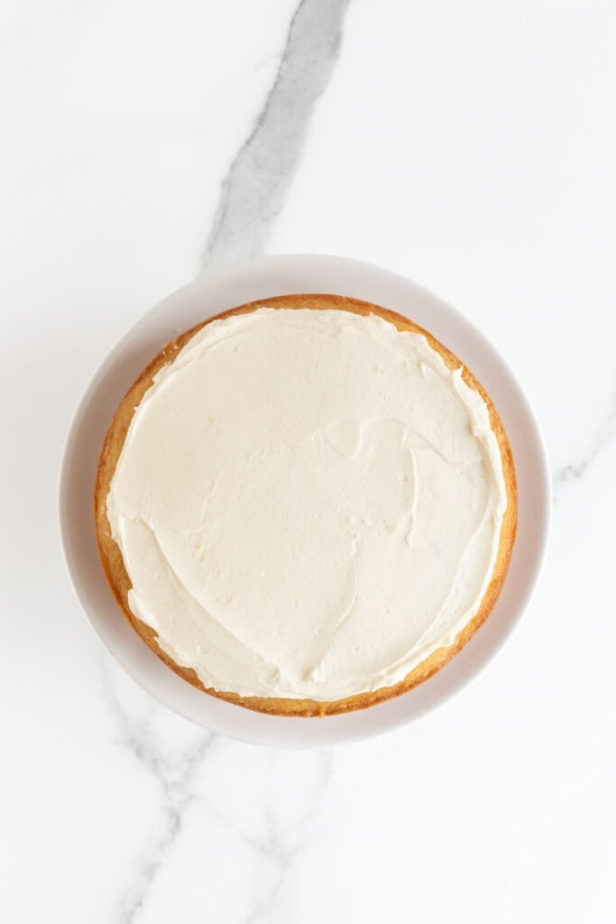 Vanilla buttercream being spread on a vanilla cake recipe
