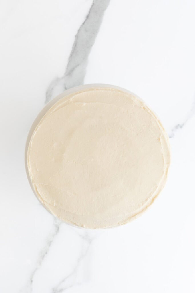 Frosted vanilla cake on white countertop
