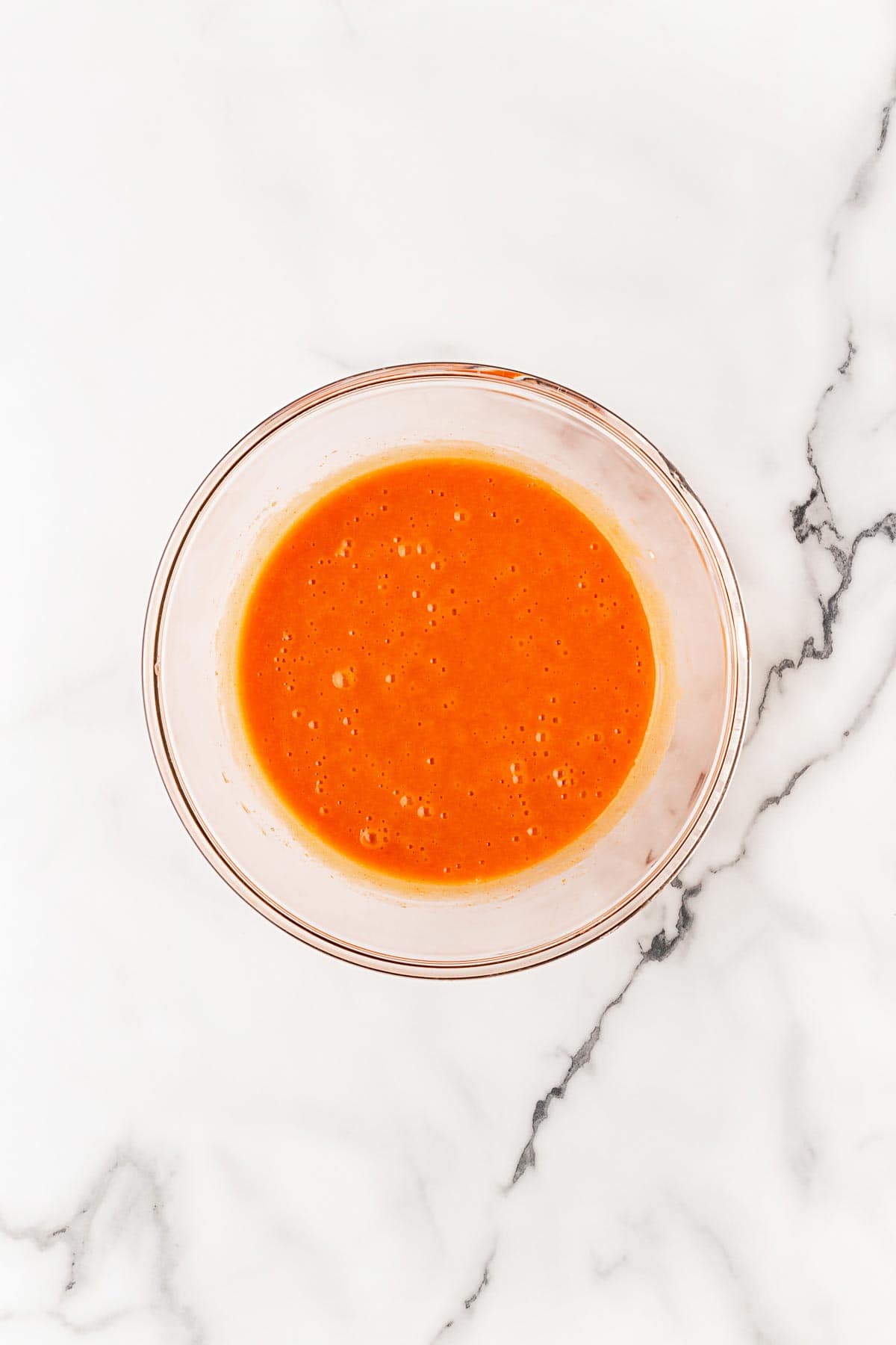 Homemade buffalo sauce in glass mixing bowl