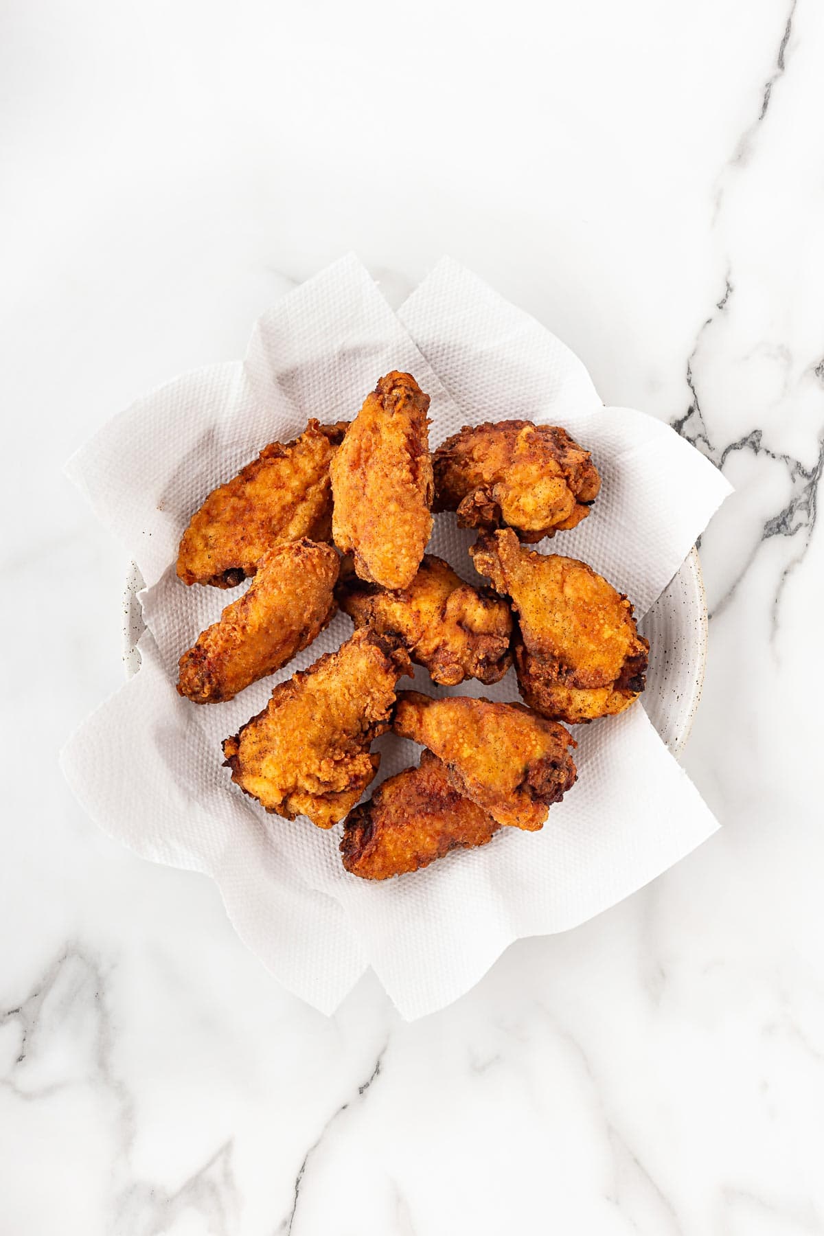 Fried chicken wings resting on paper towels after cooking