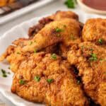 Closeup of crispy buttermilk fried chicken on a white serving platter with parsley garnish