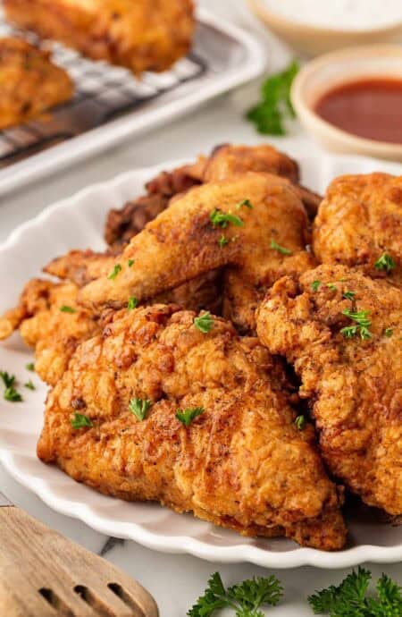 Closeup of crispy buttermilk fried chicken on a white serving platter with parsley garnish