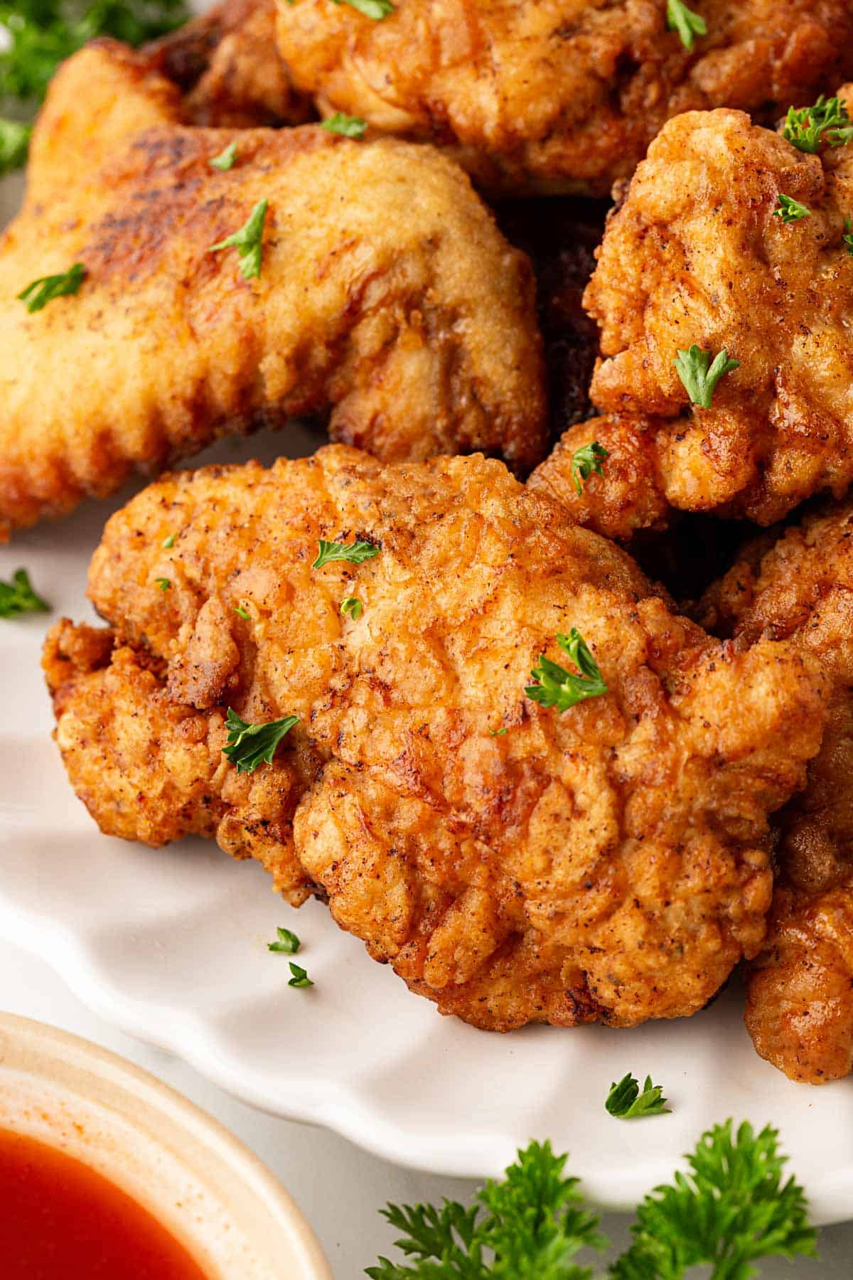 Overhead shot of crispy buttermilk fried chicken on a serving platter with ranch and hot sauce