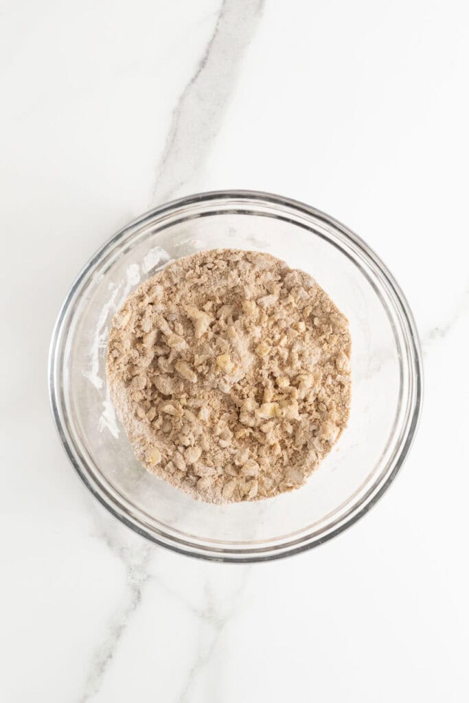 Butter added to crumble making crumbs in glass bowl