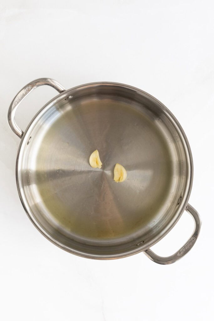 Smashed garlic cloves in a large pan 