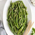 A white platter of garlic green beans ready to serve