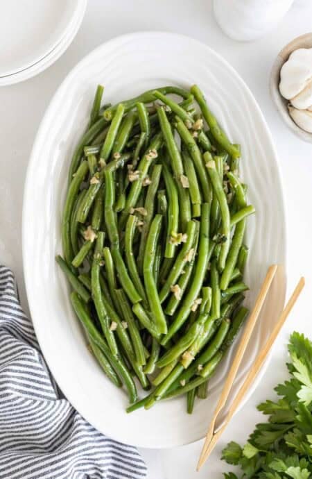 A white platter of garlic green beans ready to serve