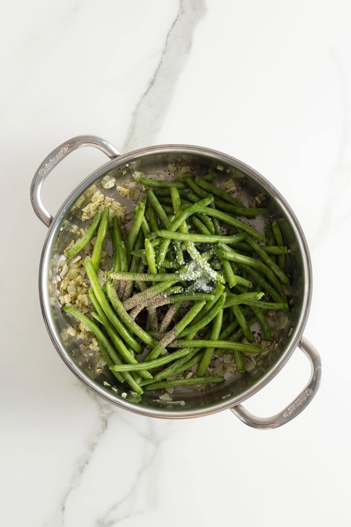 Fresh green beans added to the skillet with cooked onions and seasoning