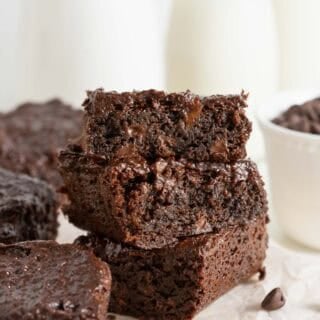 Closeup of three sweet potato brownies stacked on top of each other, showing a gooey chocolate interior and melted chips