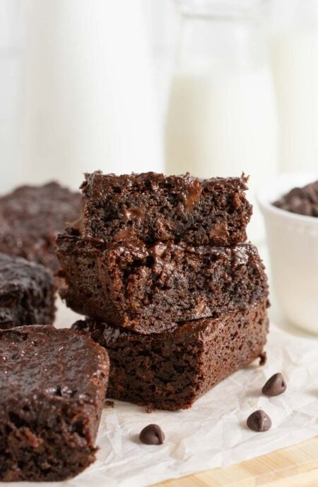 Closeup of three sweet potato brownies stacked on top of each other, showing a gooey chocolate interior and melted chips