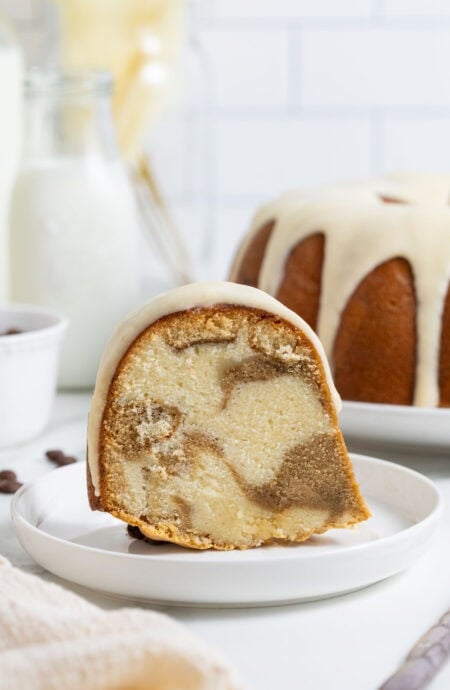 A single slice of tiramisu pound cake on a small plate in front of the whole cake