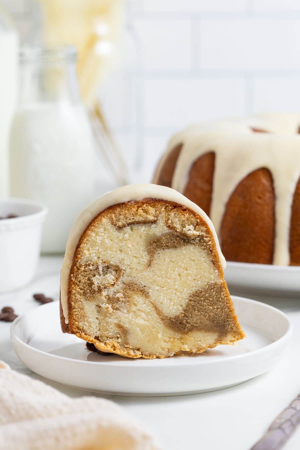 A single slice of tiramisu pound cake on a small plate in front of the whole cake