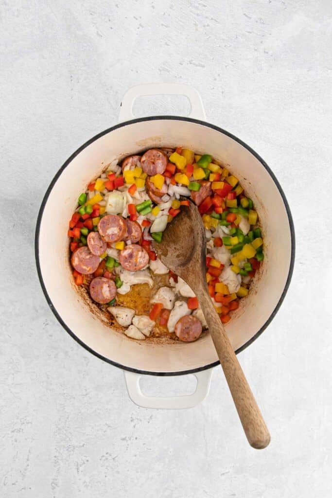Sausage, onion and peppers in a pot being stirred