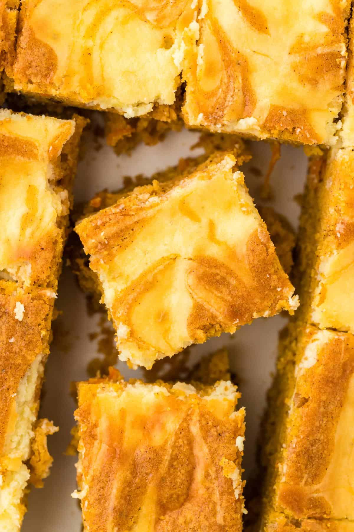 Overhead shot of swirled carrot cake bars cut into squares, with one piece lifted