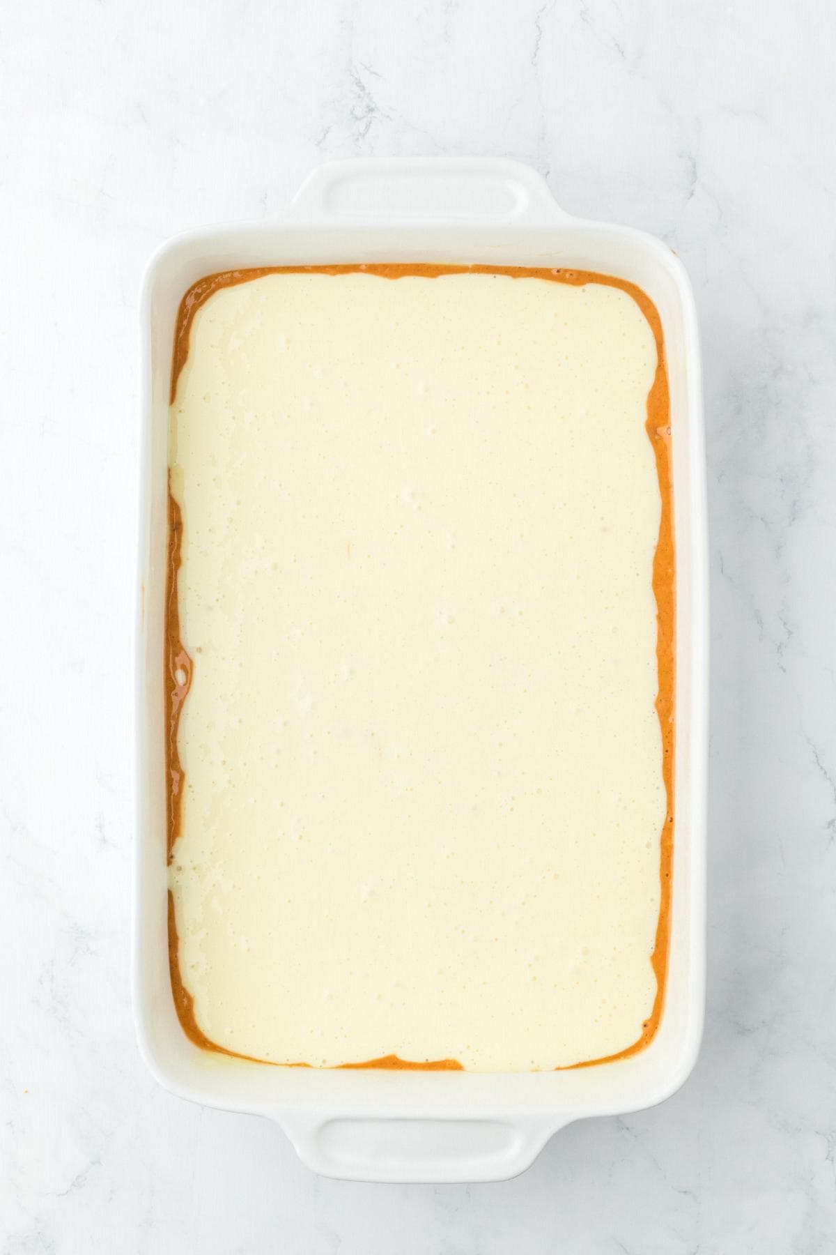 Cream cheese layer spread over carrot batter in baking dish