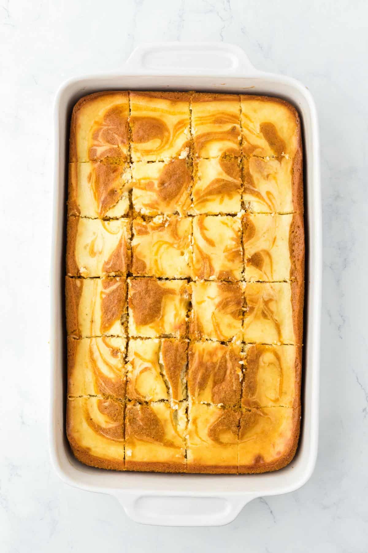 Baked carrot cake bars cut into squares in a white baking dish