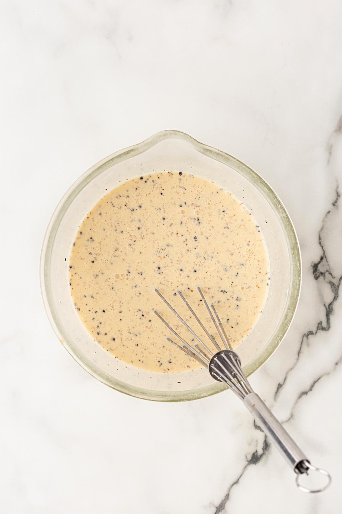 Evaporated milk, heavy cream, eggs, black pepper, and nutmeg whisked together in a glass bowl