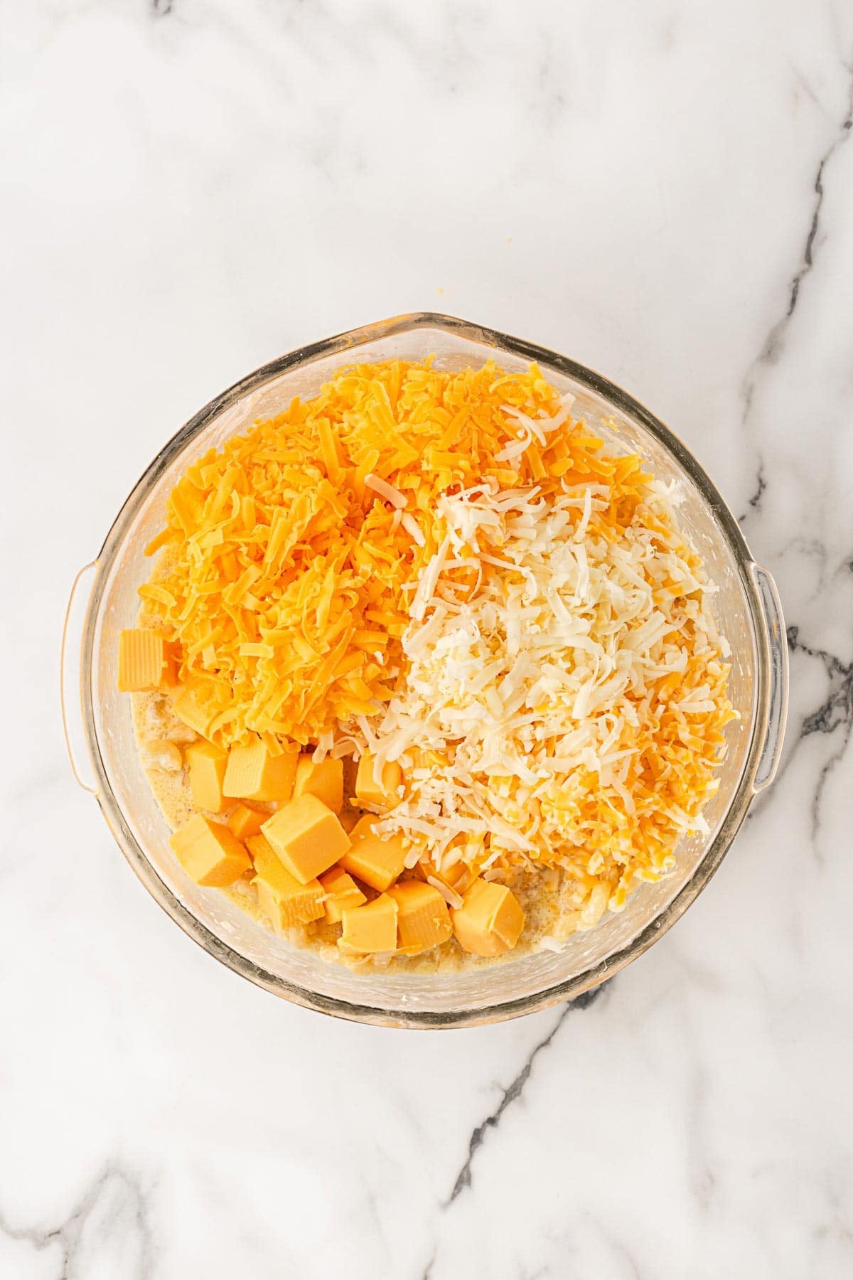 Shredded cheeses and cubed Velveeta added to the macaroni mixture