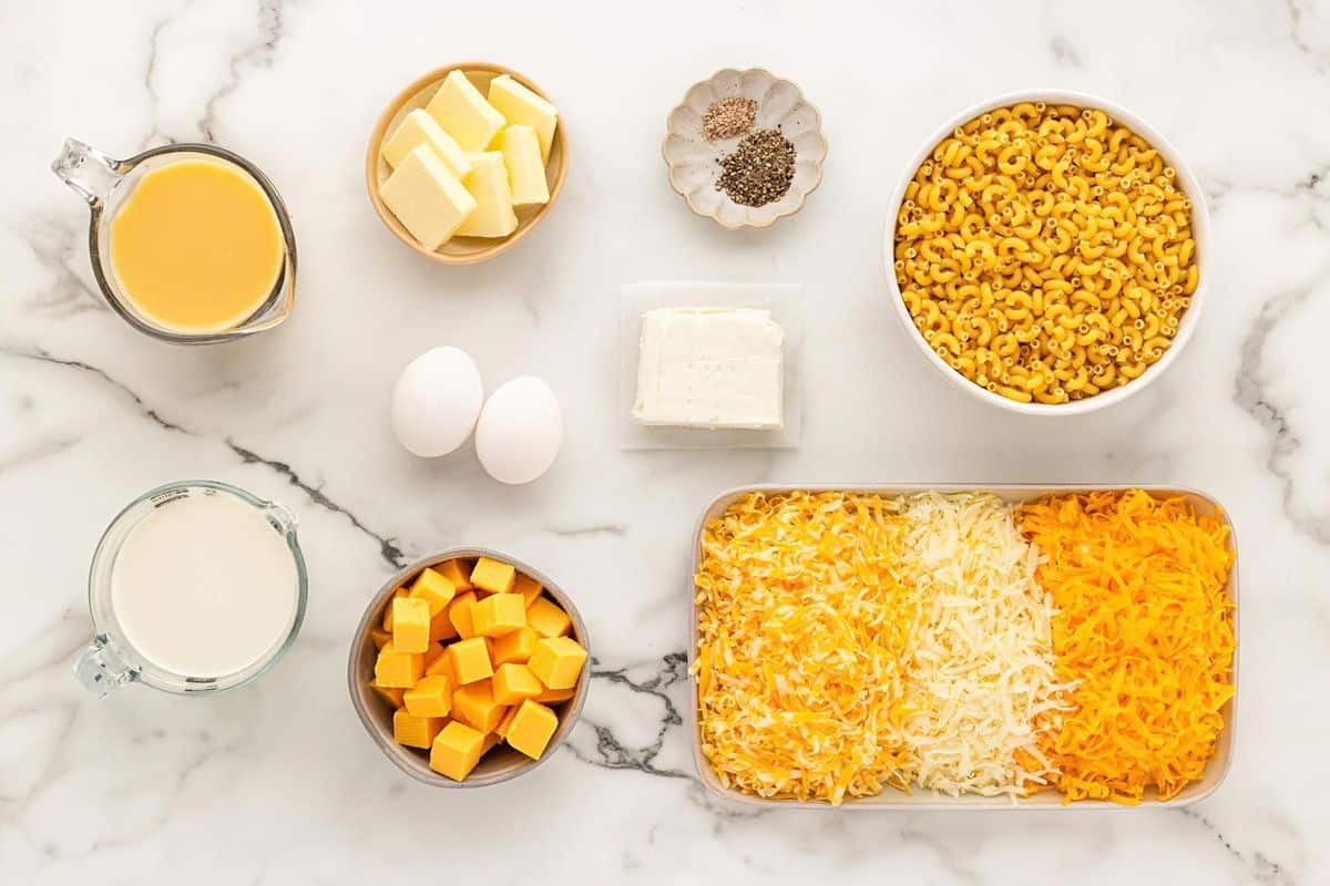 Baked mac and cheese ingredients with elbow macaroni, cheeses, eggs, butter, cream, and seasonings