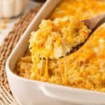 Spoonful of creamy baked mac and cheese with eggs lifted from the casserole with melted cheese stretching