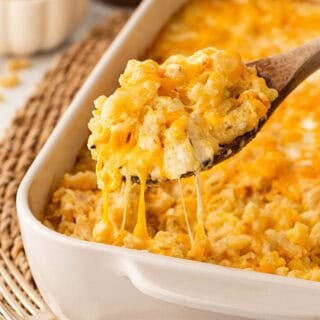 Spoonful of creamy baked mac and cheese with eggs lifted from the casserole with melted cheese stretching