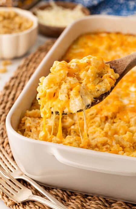 Spoonful of creamy baked mac and cheese with eggs lifted from the casserole with melted cheese stretching