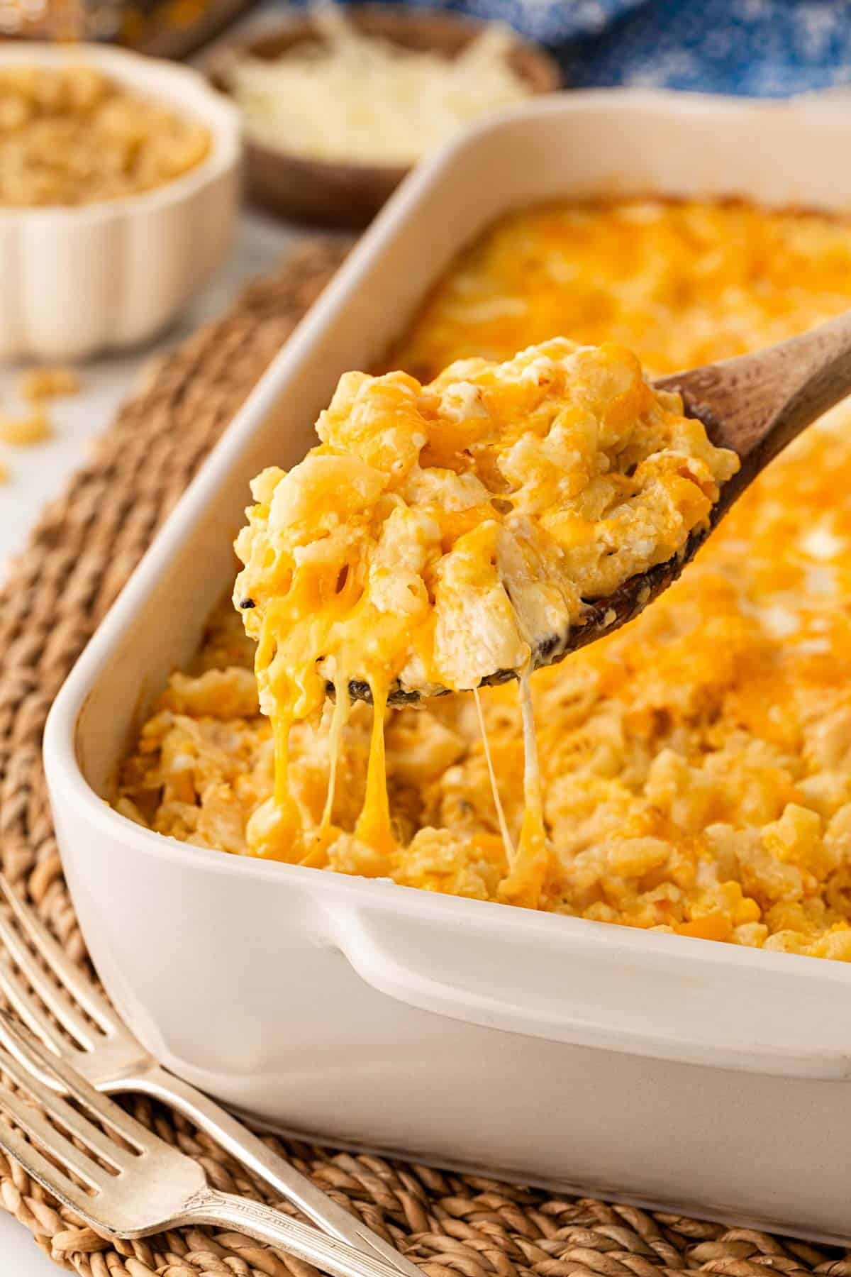 Spoonful of creamy baked mac and cheese with eggs lifted from the casserole with melted cheese stretching