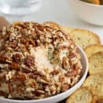 Closeup of the cheese ball with pecan coating, surrounded by toasted bread slices
