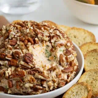 Closeup of the cheese ball with pecan coating, surrounded by toasted bread slices