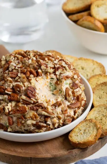Closeup of the cheese ball with pecan coating, surrounded by toasted bread slices