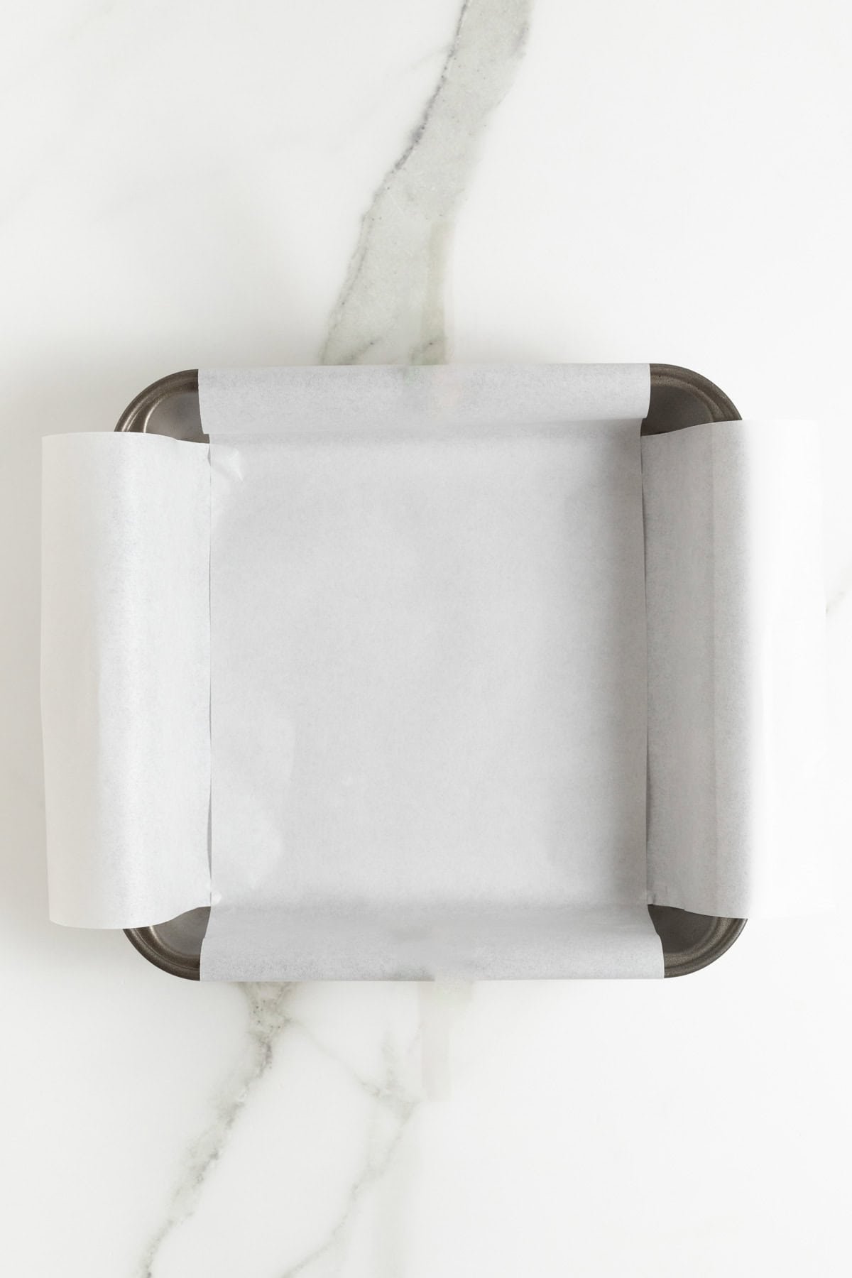 Metal baking pan lined with parchment paper, ready for fudge