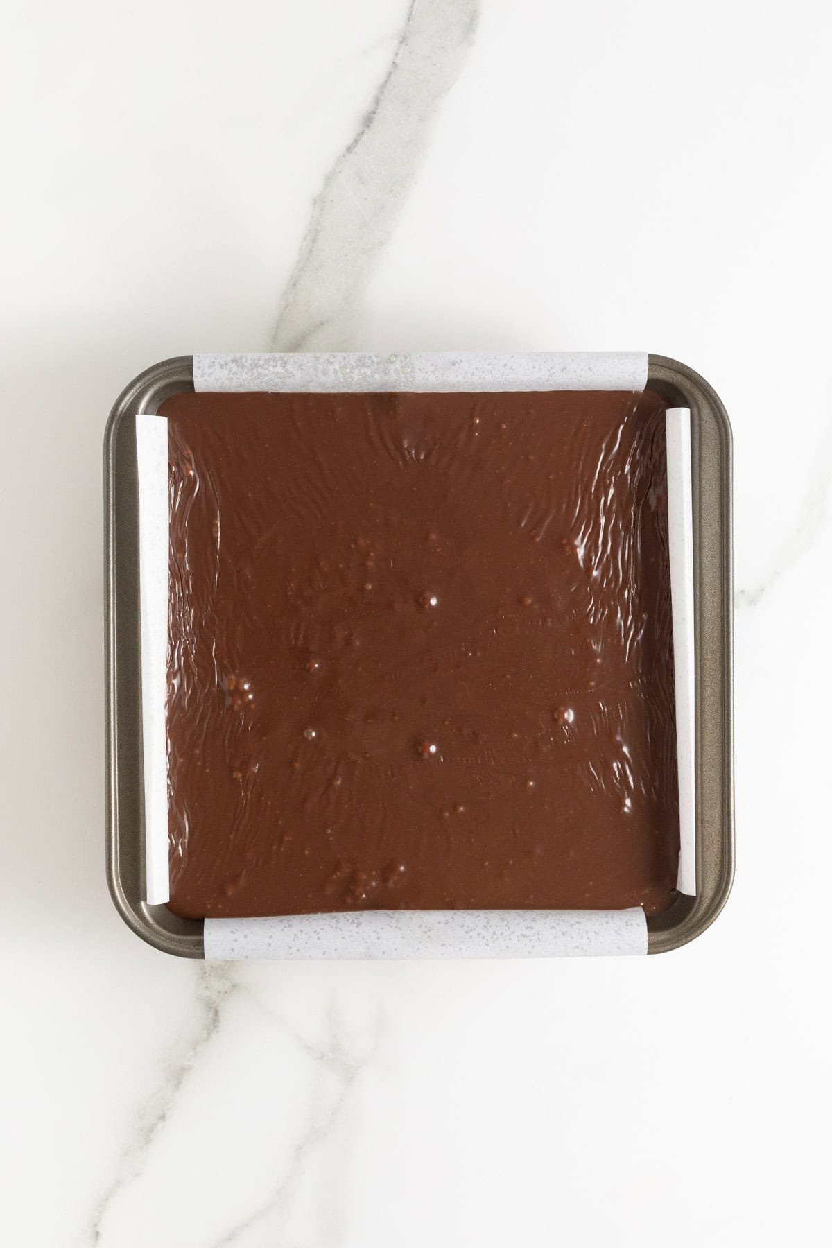 Fudge mixture poured into a parchment-lined pan, still warm and unset