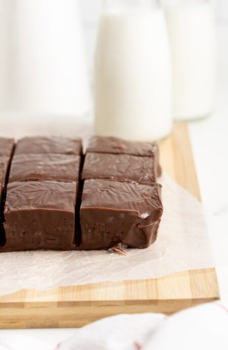 Side angle of chocolate fudge squares with milk bottles blurred in background