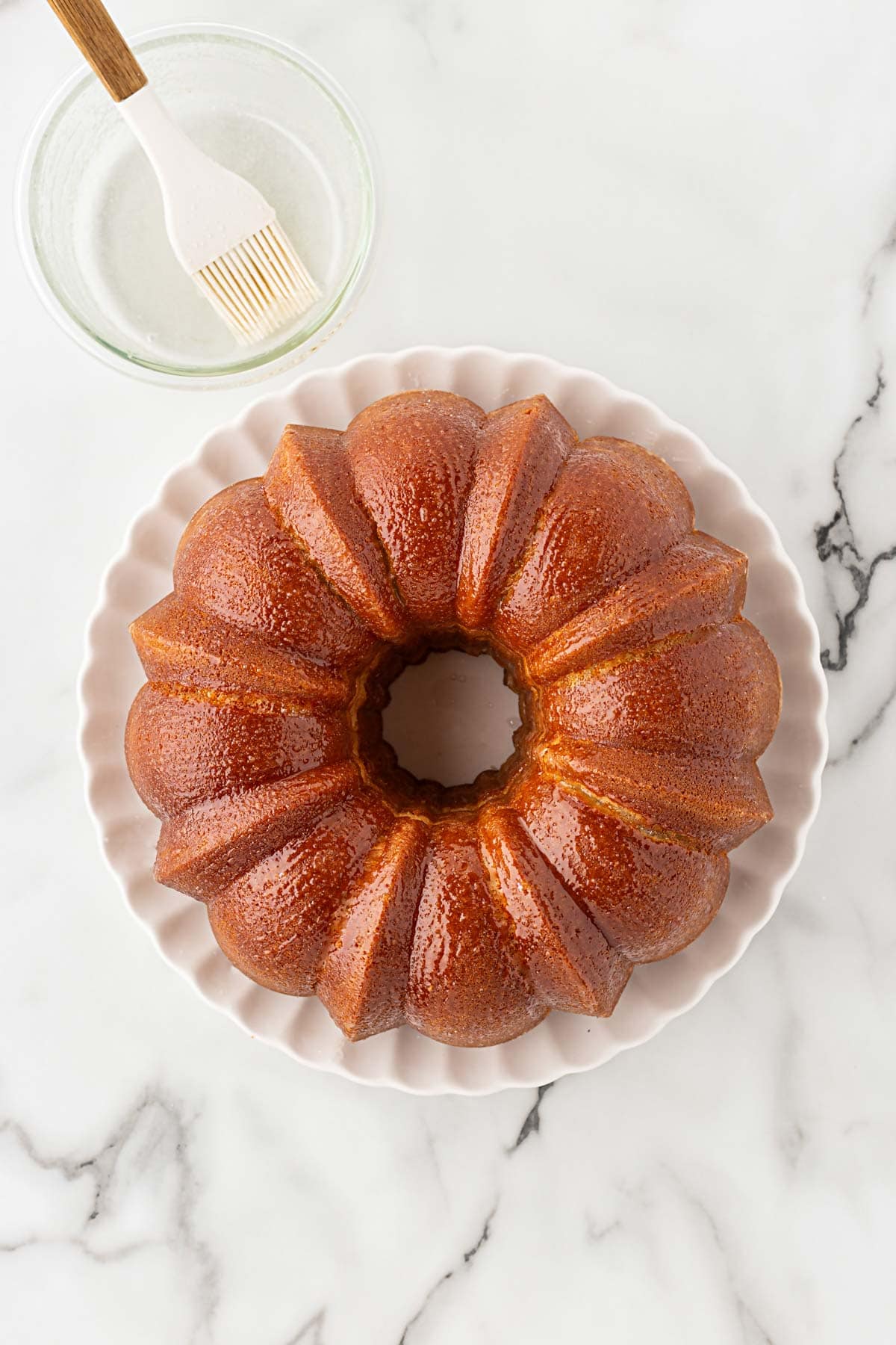 Bundt cake brushed with glaze before being coated in cinnamon sugar