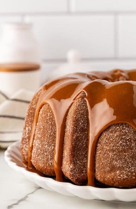 Closeup of churro pound cake covered in dulce de leche glaze dripping down the sides