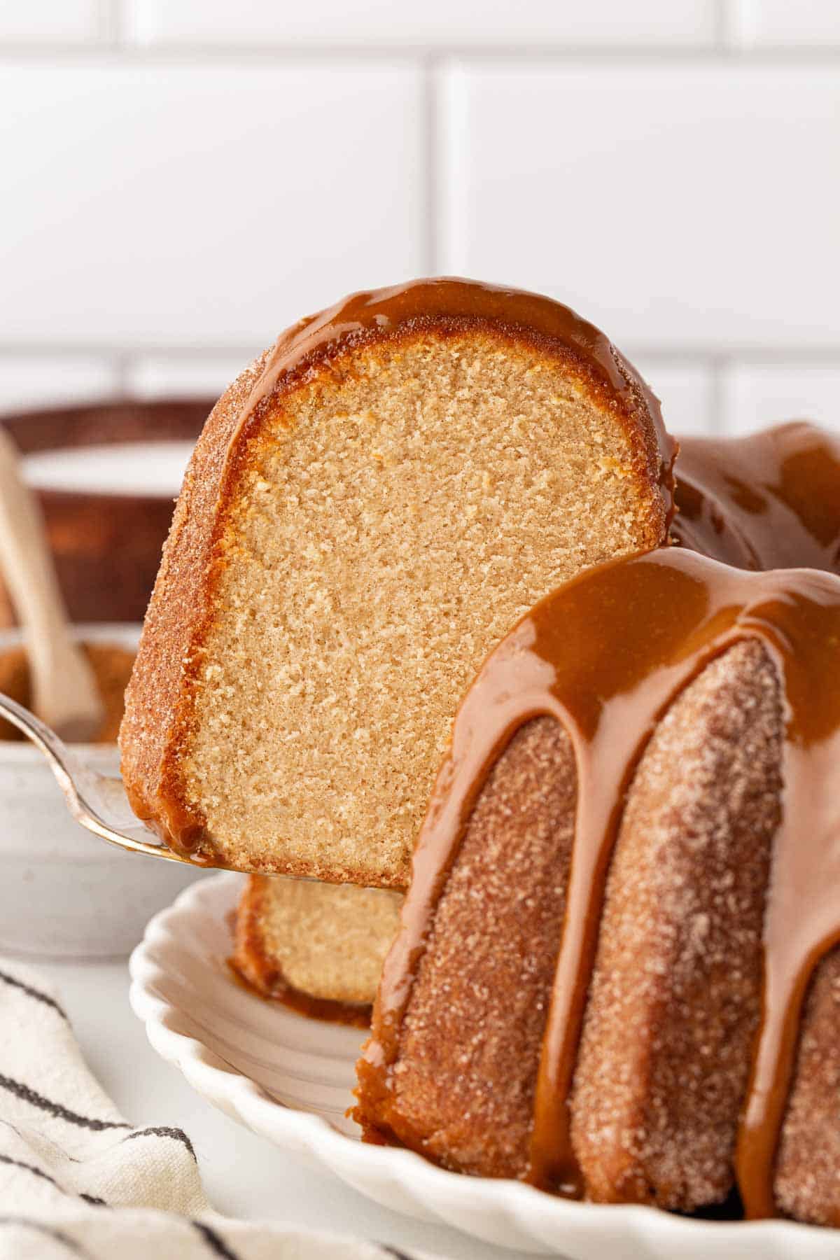 A slice of churro pound cake being lifted, showing the soft and fluffy interior with dulce de leche glaze on top