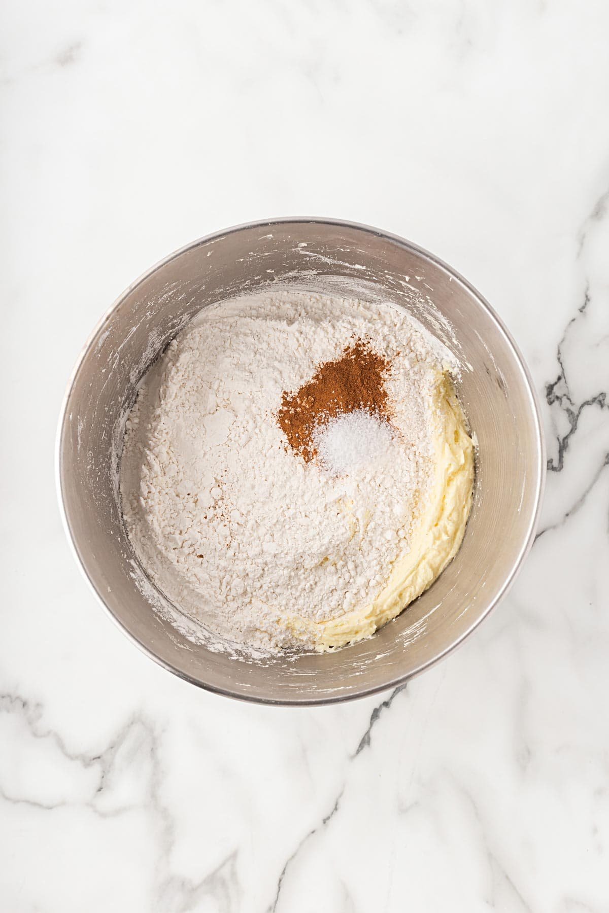Mixing bowl filled with flour, cinnamon, and salt added to the batter