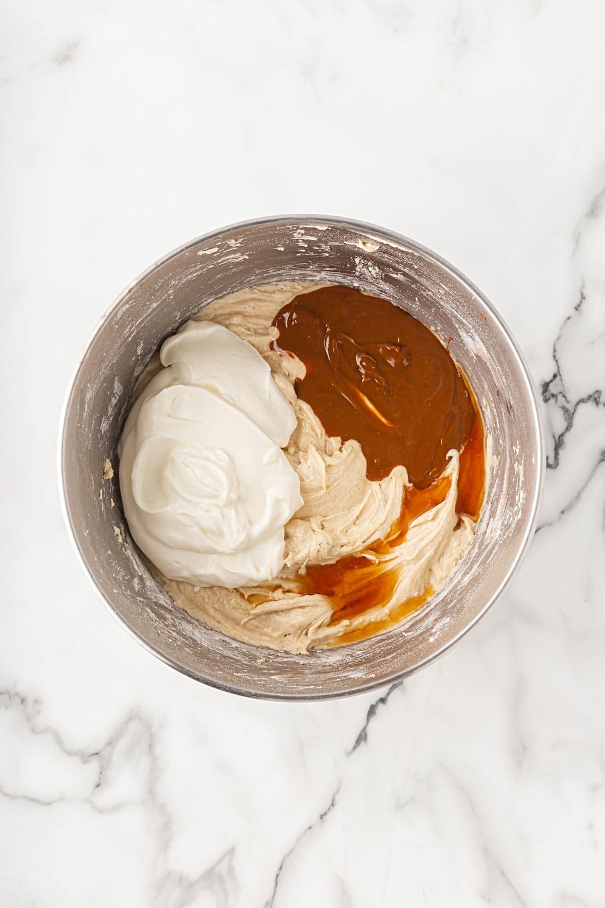 Batter in a bowl with sour cream and dulce de leche sauce added but not yet mixed