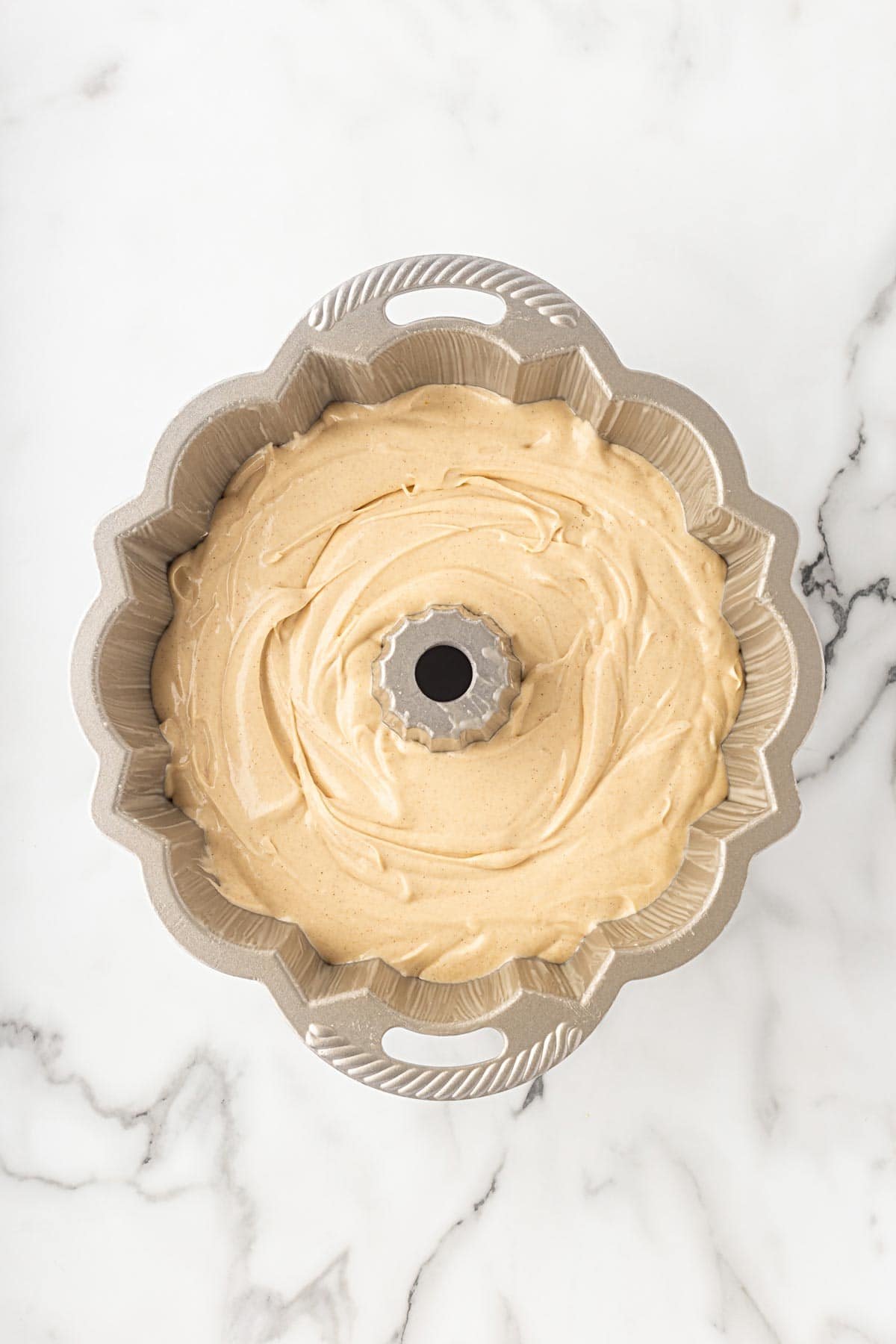 Raw churro pound cake batter spread evenly in a Bundt pan