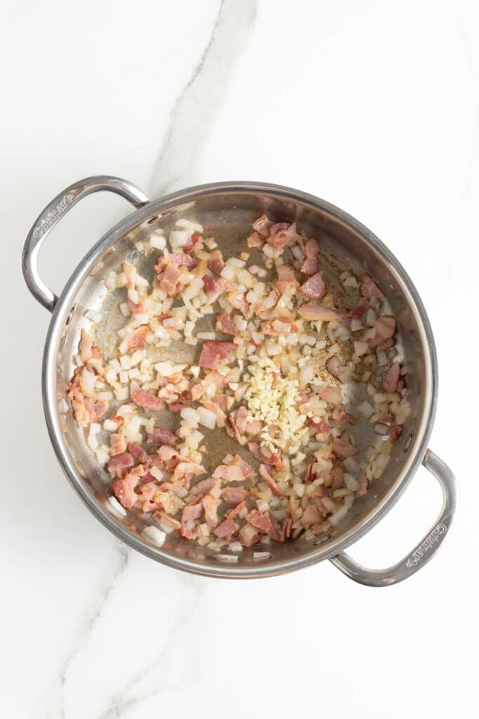 Bacon, onion and garlic in a skillet being cooked