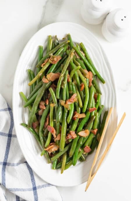 Green beans with bacon on a white platter ready to enjoy
