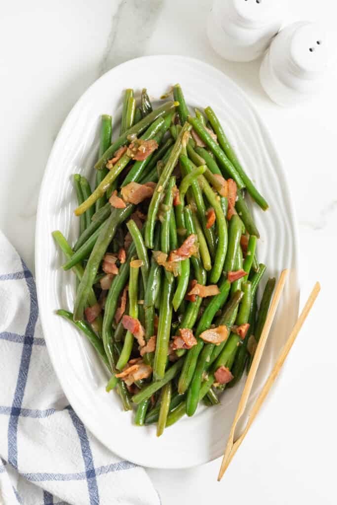 Green beans with bacon on a white platter ready to enjoy