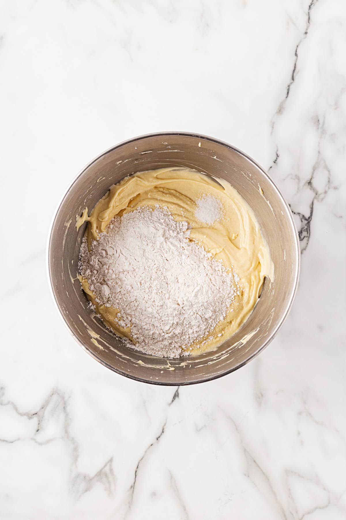 Smooth batter in a bowl with flour and salt added on top before final mixing