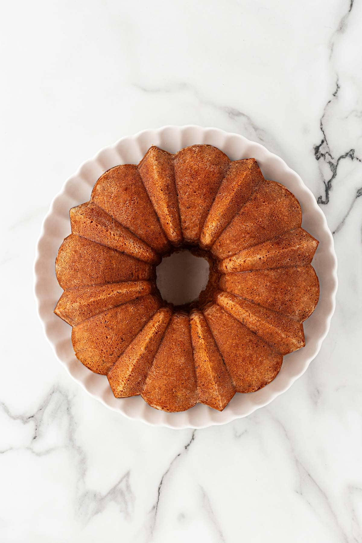 Fully baked golden-brown butter pecan pound cake cooling on a plate with a crisp exterior