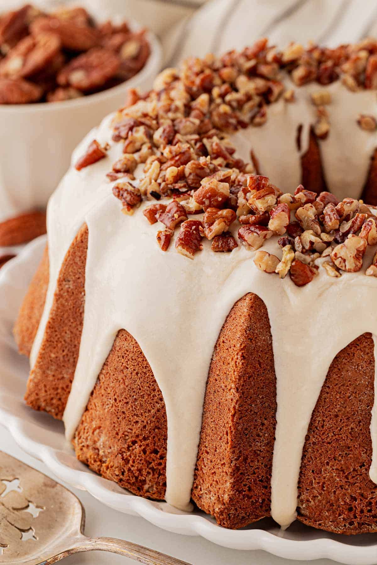 Closeup of the butter pecan pound cake showing the thick glaze dripping over the golden crust and topped with chopped toasted pecans