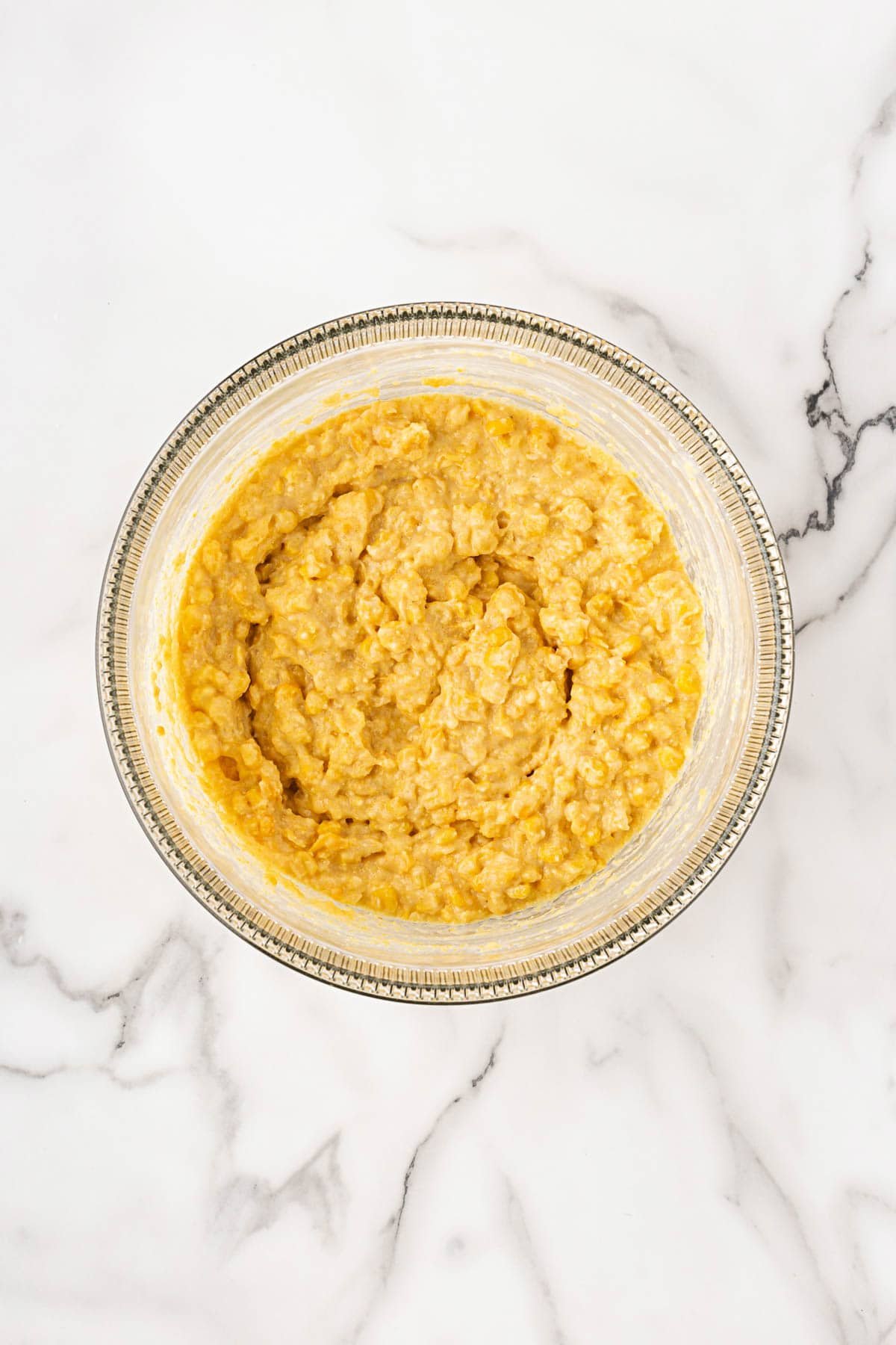 Cornbread pudding batter combined and smooth in a clear glass bowl