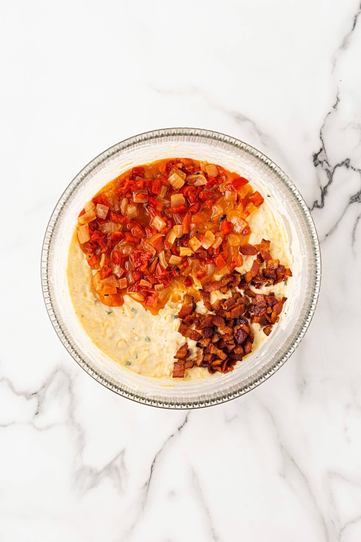 Mixture in a bowl with sautéed peppers, onions, and bacon added to the batter