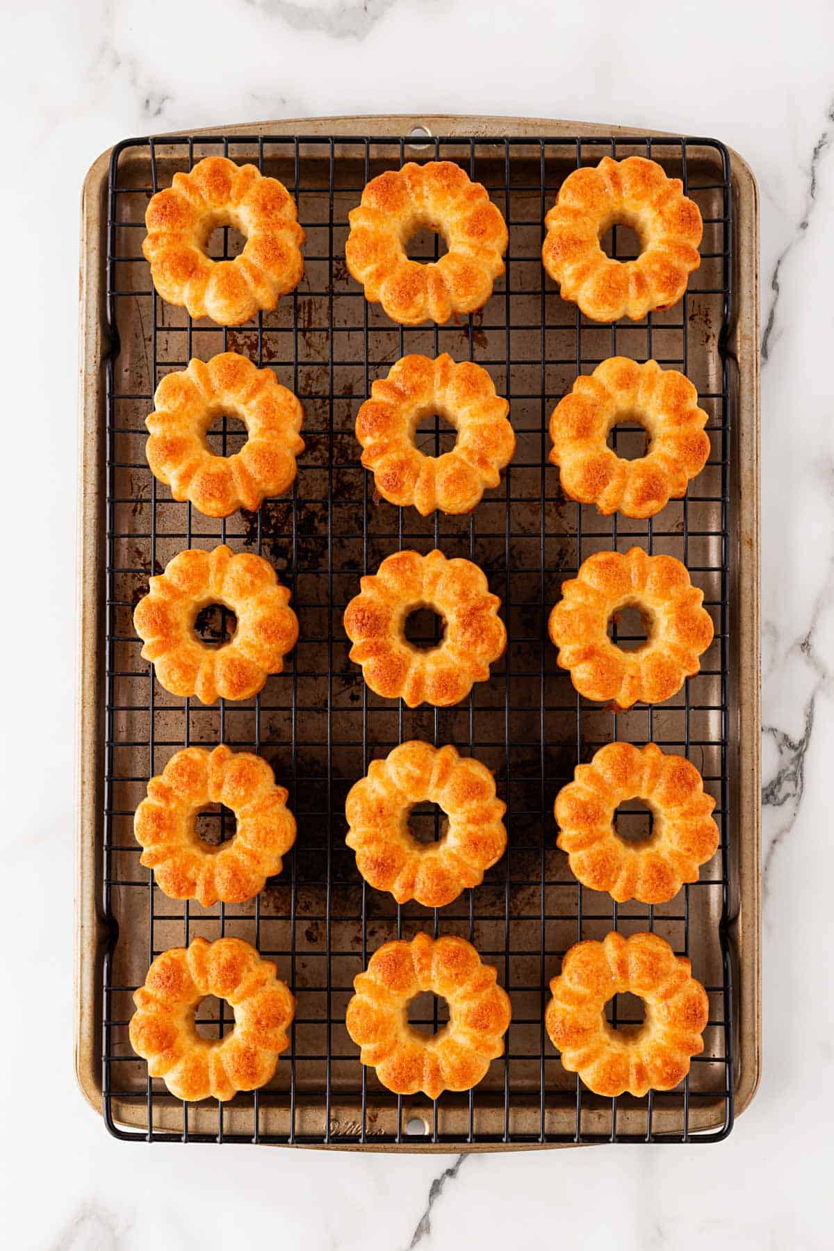 Mini honey bundt cakes fresh out of the oven, golden brown, still in the silicone baking mold on a cooling rack