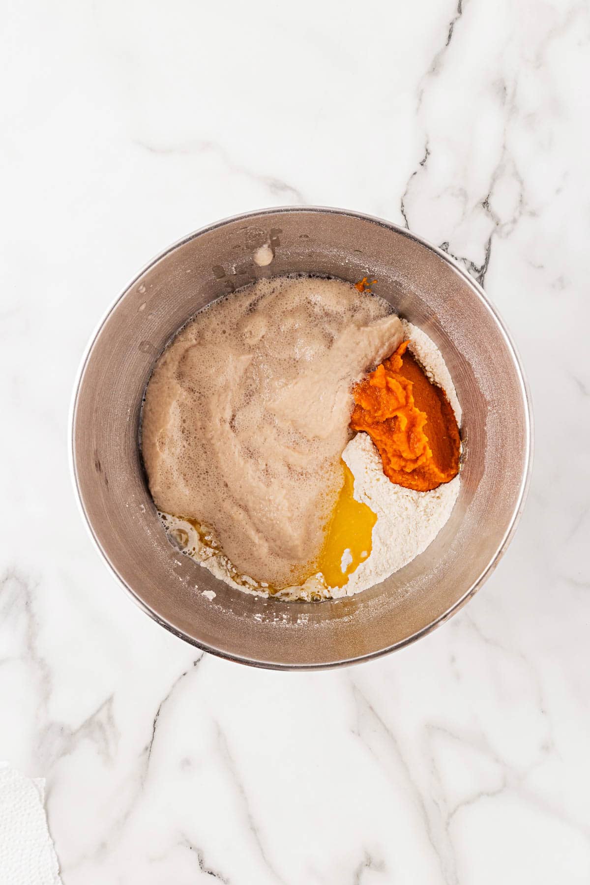 Mixing bowl with flour, pumpkin purée, melted butter, and yeast mixture