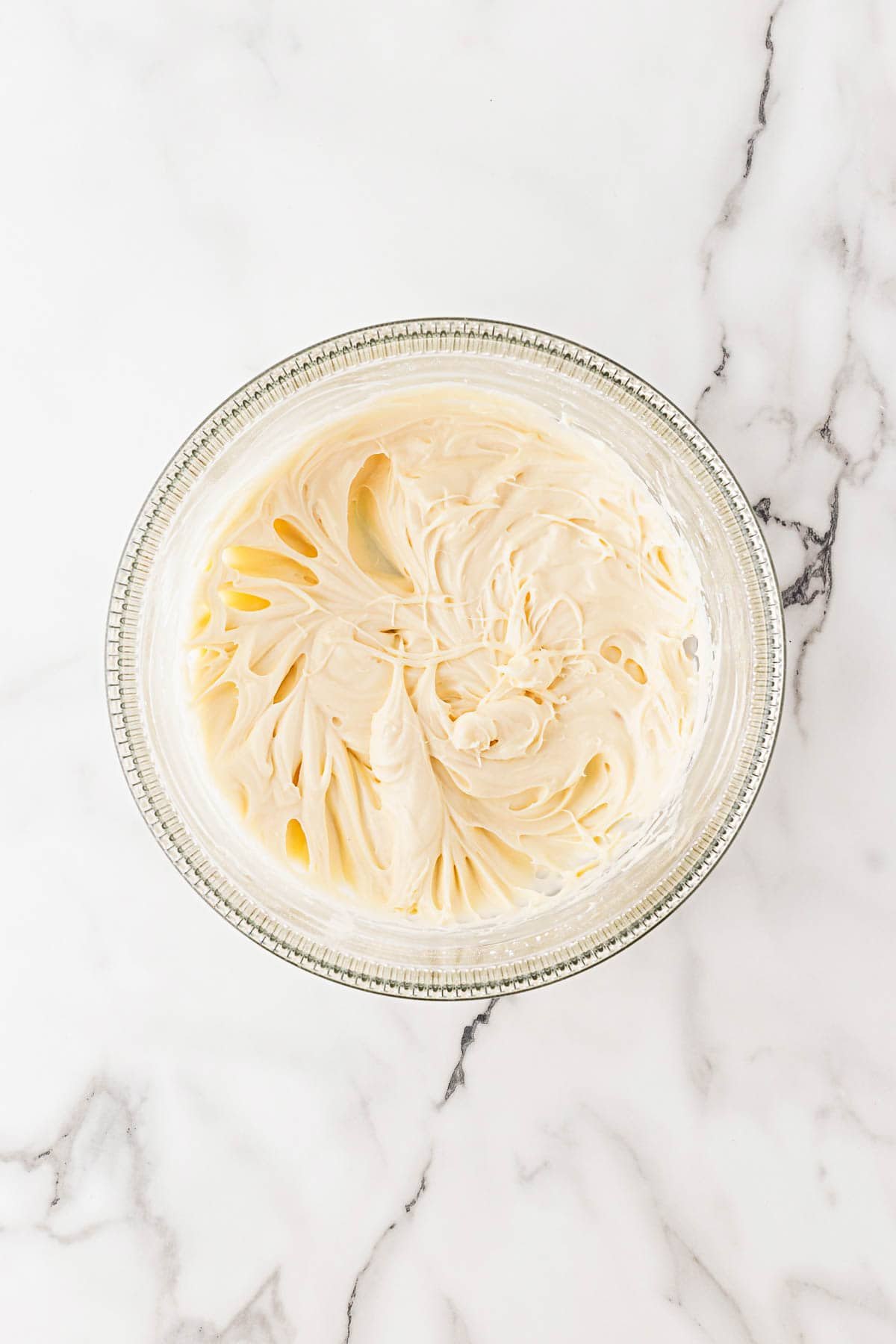 Bowl of creamy frosting swirled to a smooth, fluffy consistency